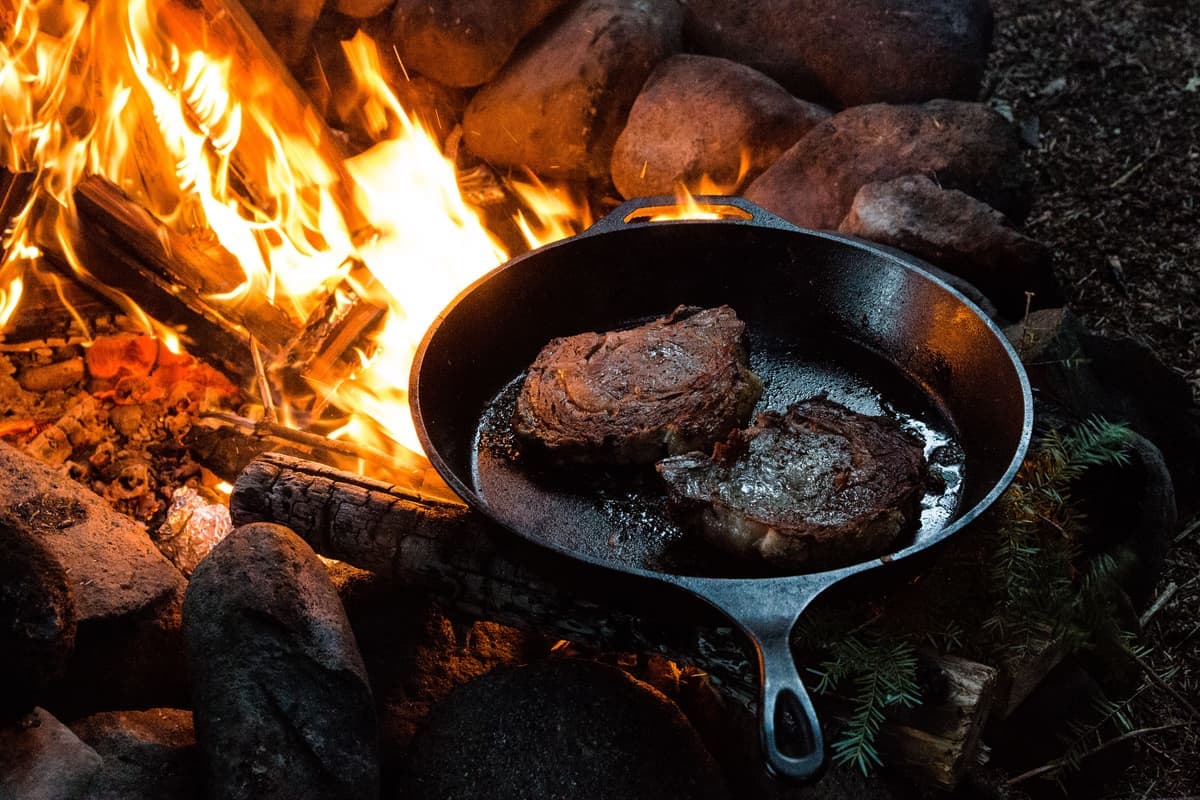 A steak searing in a hot cast iron skillet, edges browning